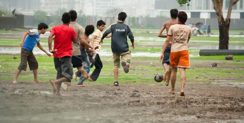 Kids playing soccer on rain soaked mud (are soccer games canceled for rain?)