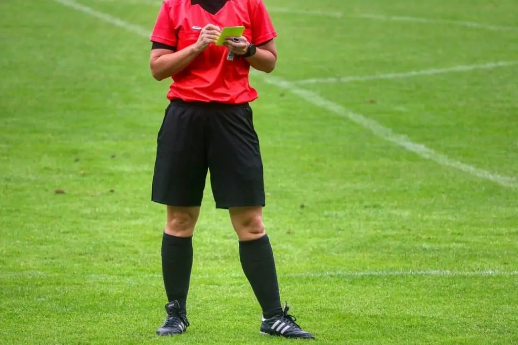 Soccer referee writing on a yellow card