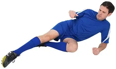 soccer player on the ground in a slide tackle