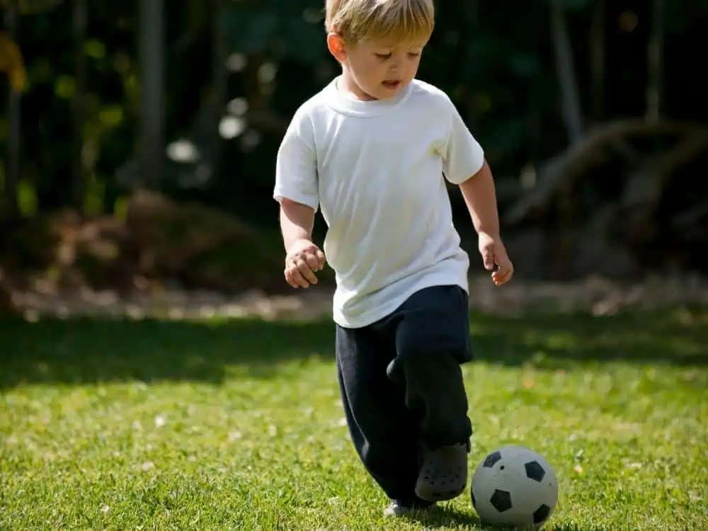 Child 3 or 4 dribbling a soccer ball in a park