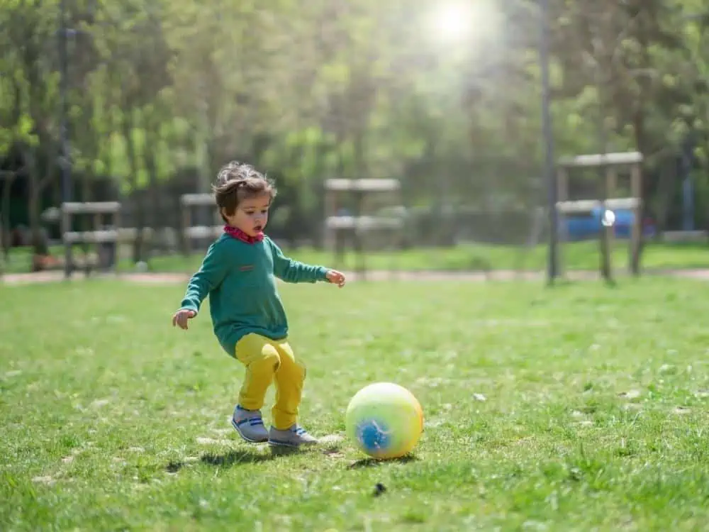 Child 3 or 4 playing soccer in a park
