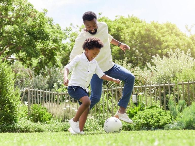 a father and son playing soccer together outdoors. ○ Soccer Blade