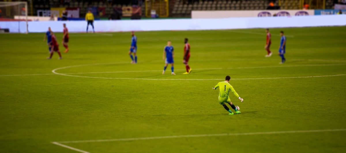 Soccer goalkeeper kicks out the ball during the match at stadium. ○ Soccer Blade