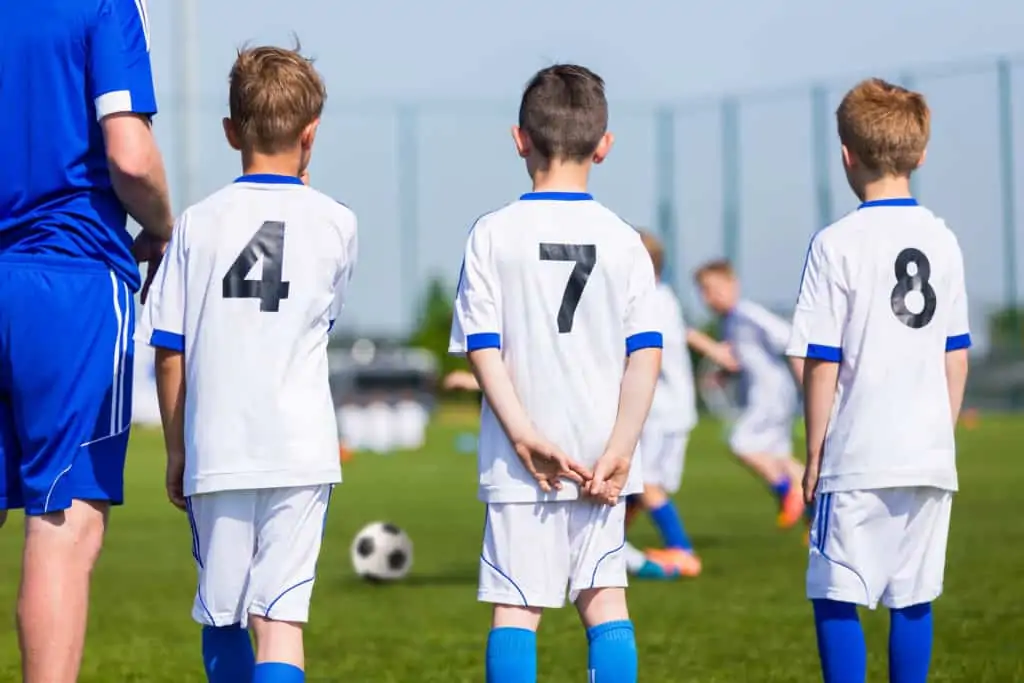 Youth Soccer Players With Their Soccer Coach Watching A Game