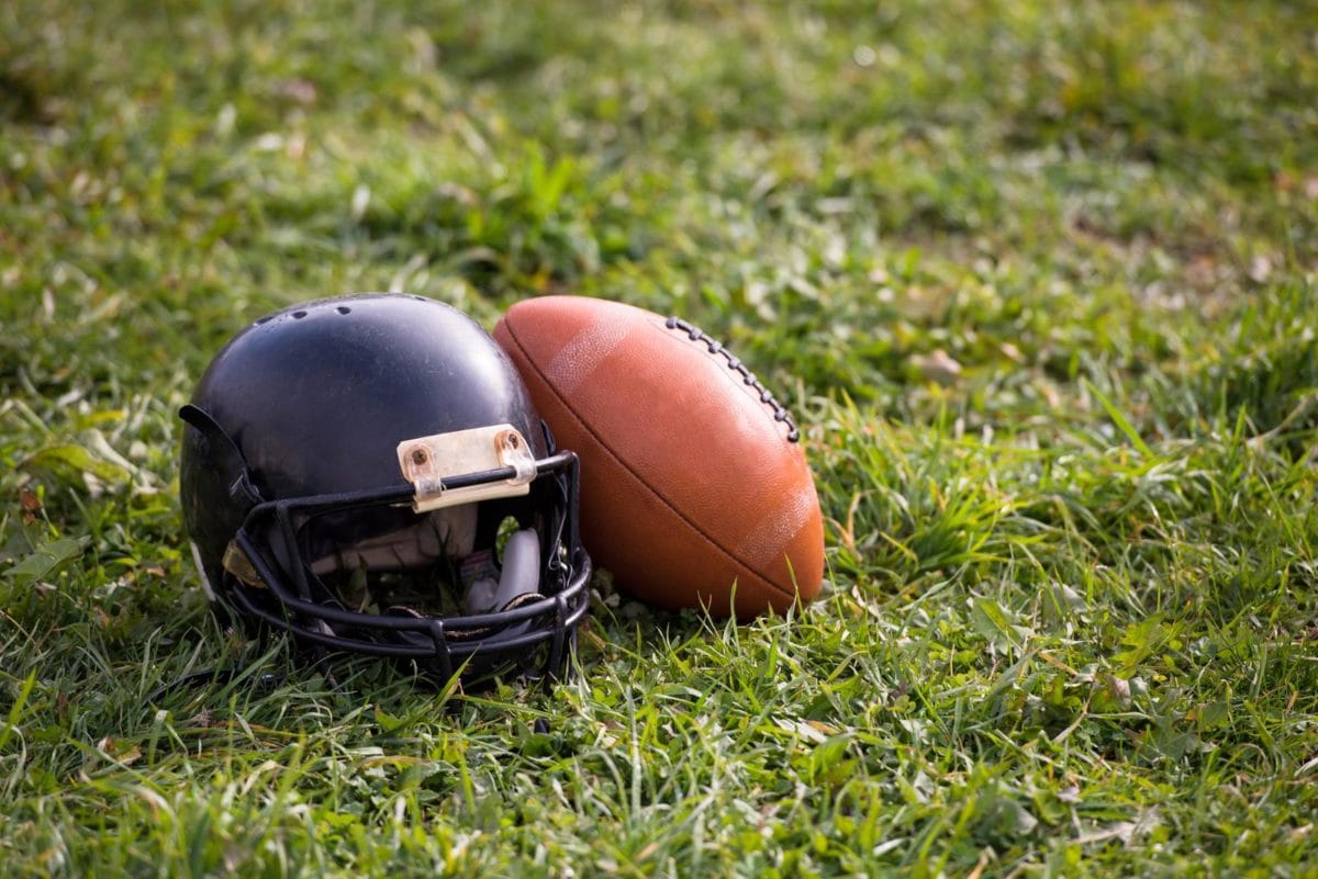 American football helmet and ball lying on field. ○ Soccer Blade