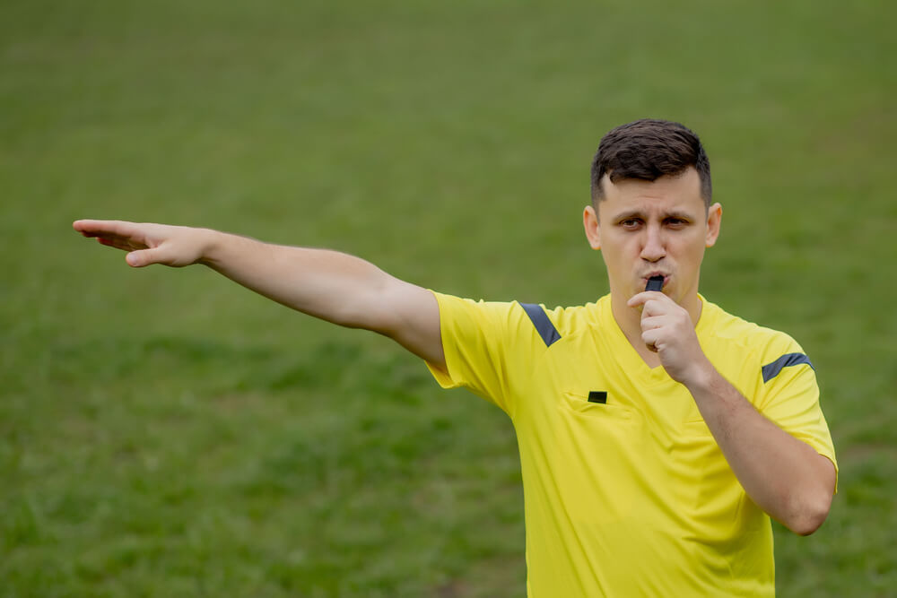 Soccer Referee Signals For A Foul - Pointing towards the opposition goal for the attacker kick.