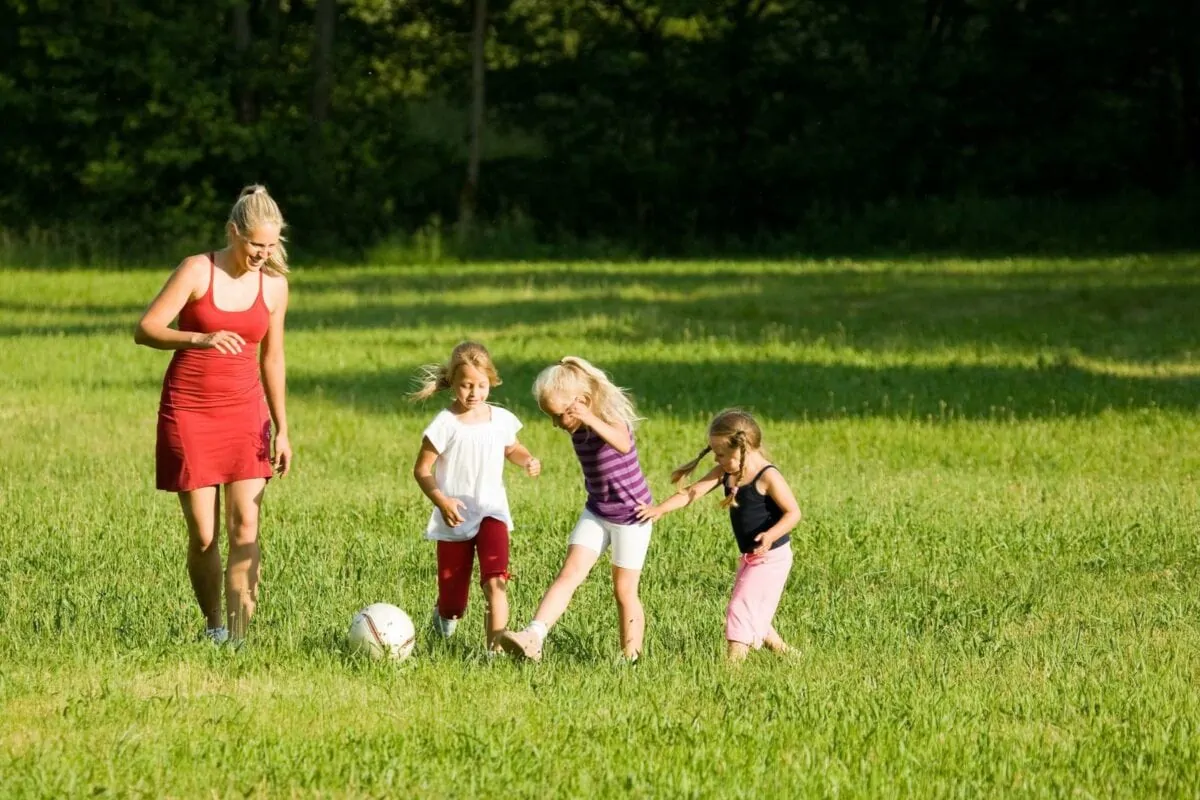 Happy family playing football well soccer for North America on a green sunlit meadow. ○ Soccer Blade