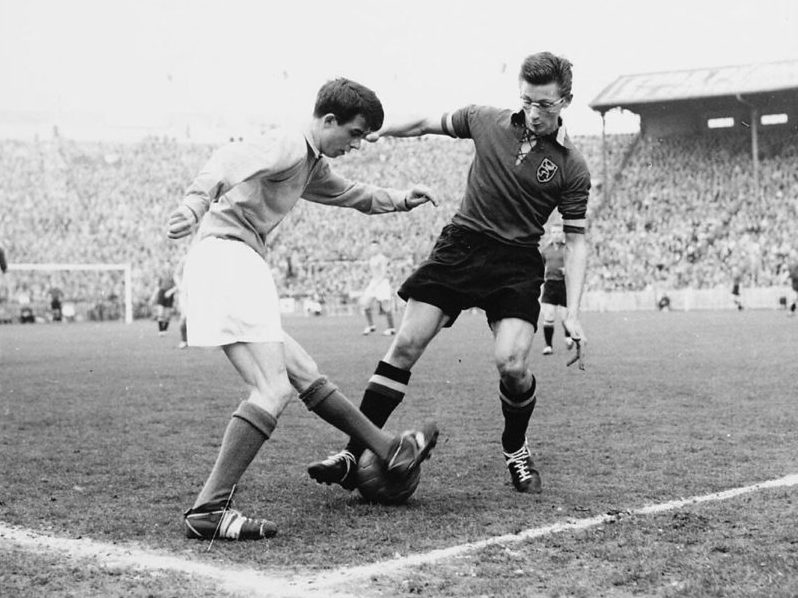 An Old Soccer Game in Black and White A player wearing glasses