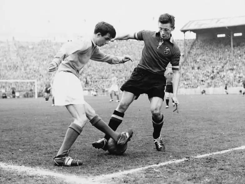 An Old Soccer Game in Black and White A player wearing glasses