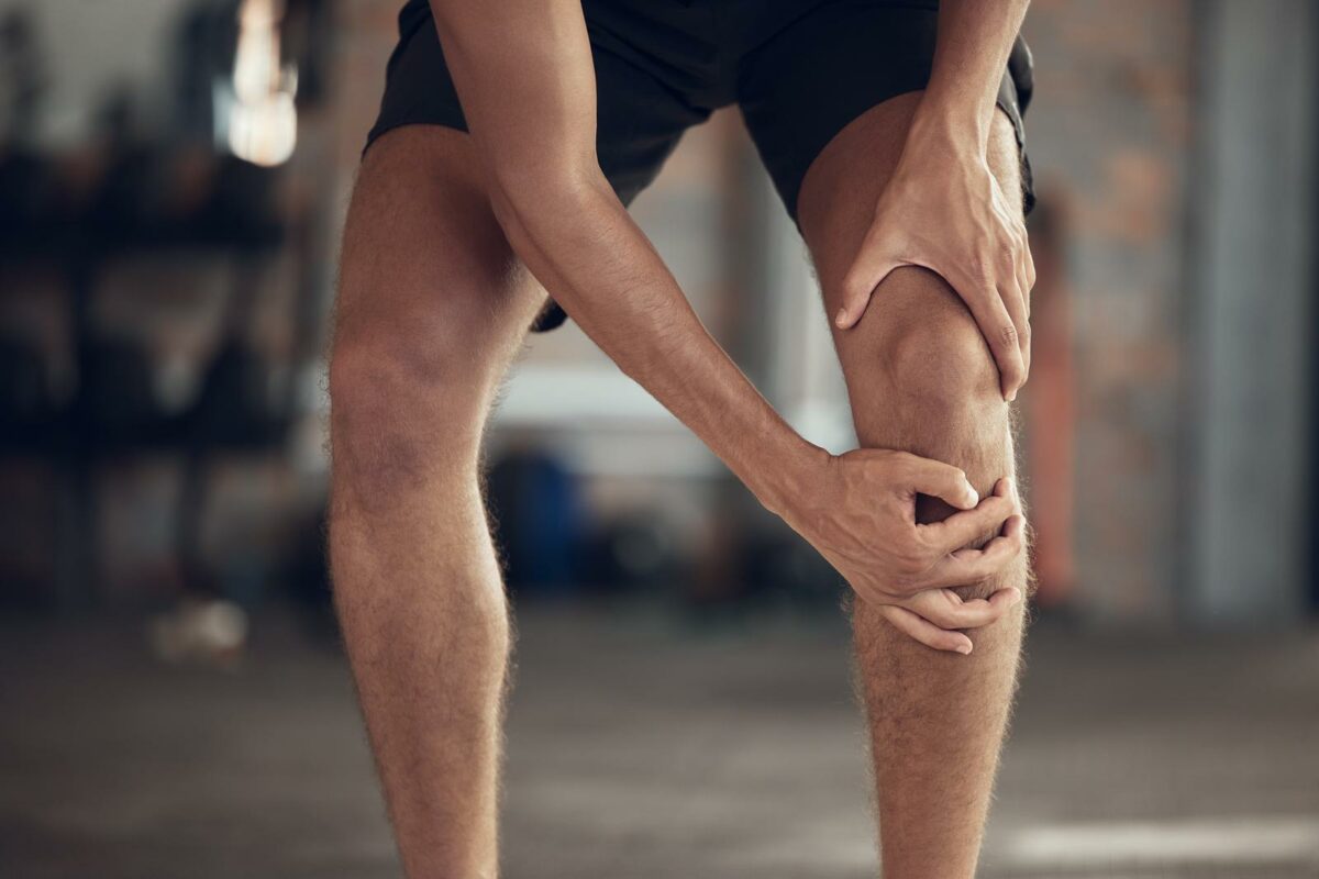 Closeup of athlete knee joint pain. Hands of fit man touching his knee in pain. ○ Soccer Blade