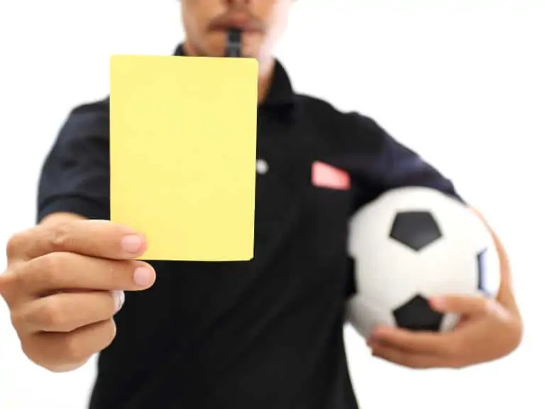 Soccer referee holding a ball and showing a yellow card