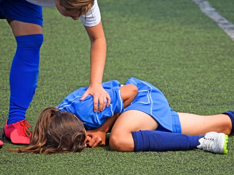 Soccer player on the ground injured holding her arm