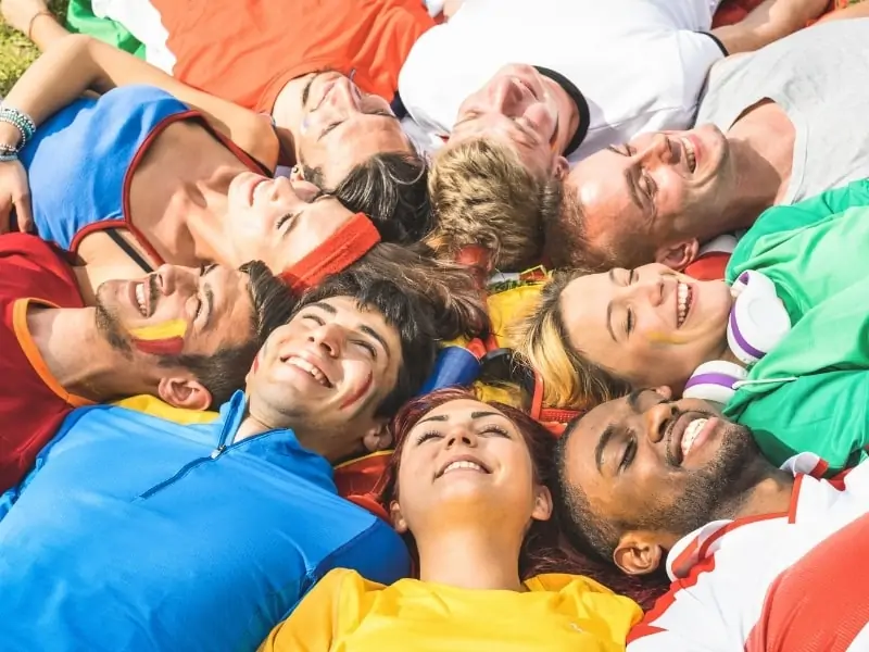 Soccer players lying in a circle next to each other dressed in colorful outfits