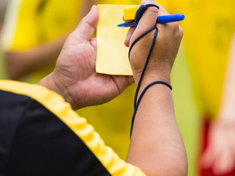 Soccer referee writing on a yellow card