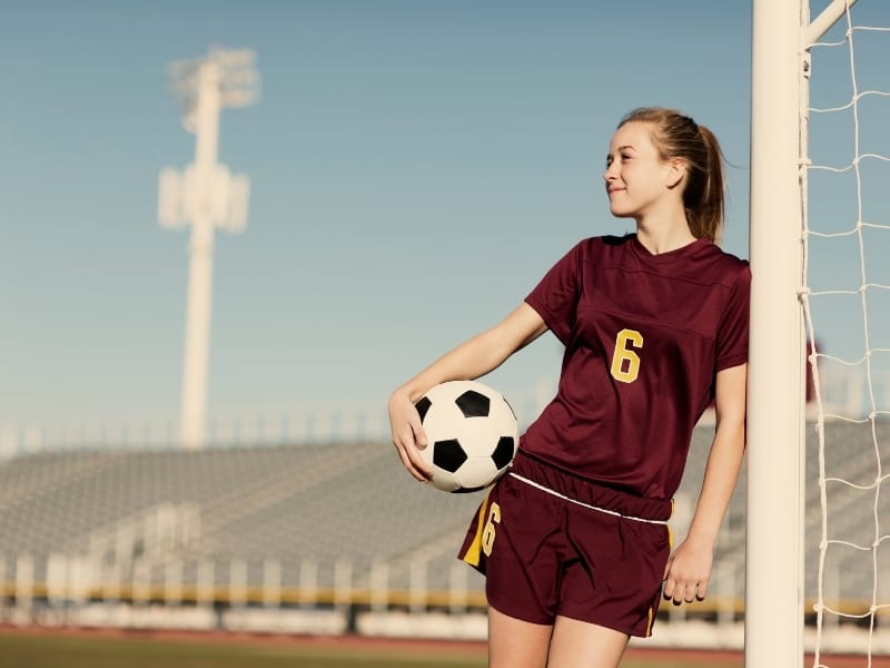 Teenager holding a ball and leaning against a goal