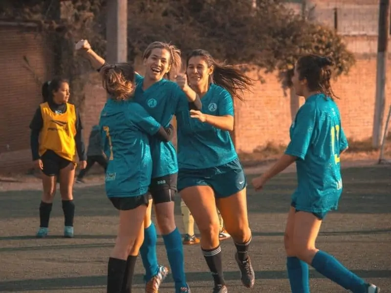 Four soccer girls celebrating a goal