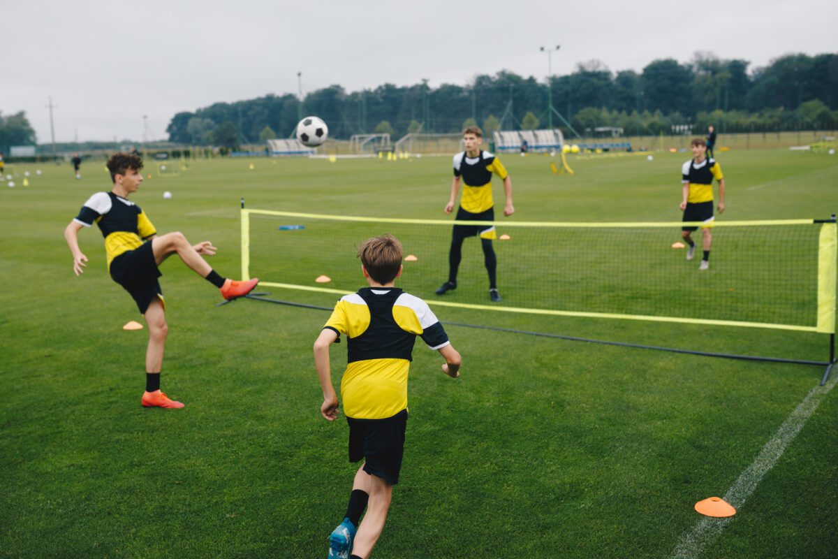 Teenagers in youth soccer team playing soccer tennis in a training game. ○ Soccer Blade