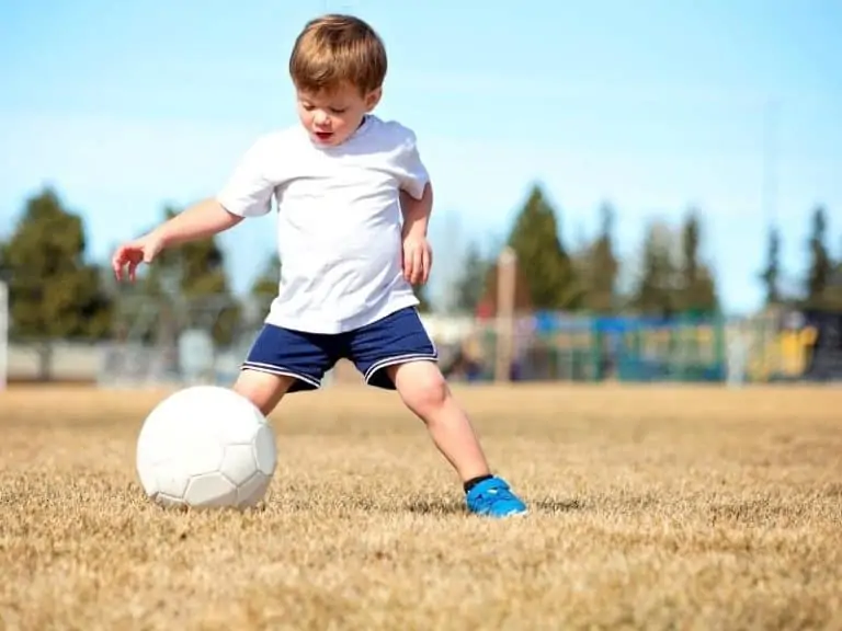 Toddler on grass playing soccer