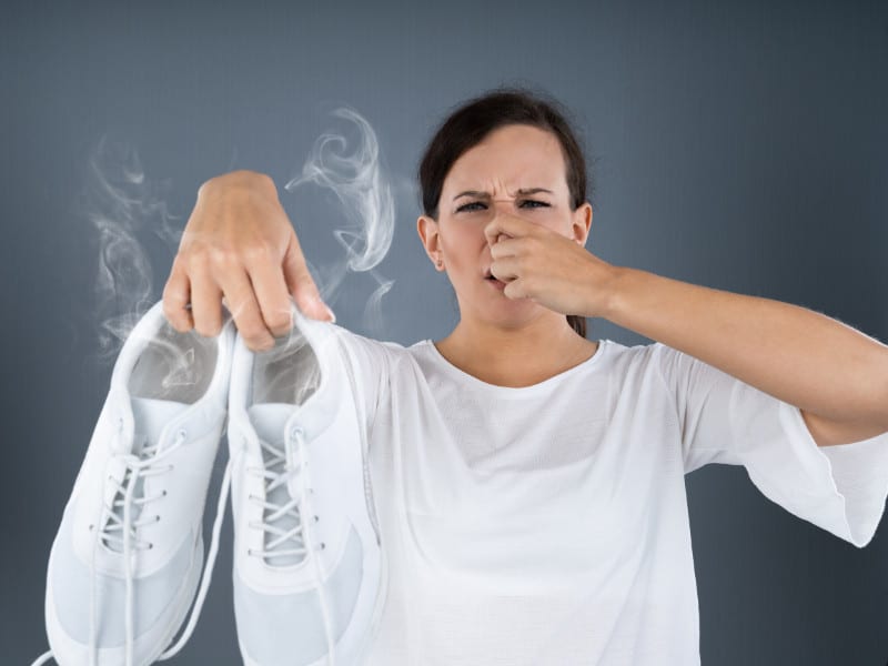 woman holding smelly shoes