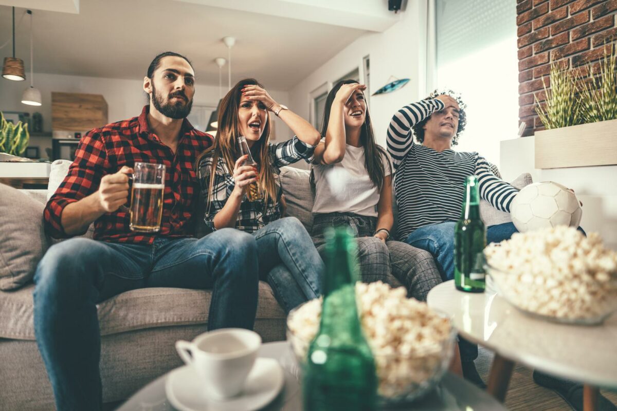 Friends are fans of sports games as soccer love spending their free time at home together. They are screaming and gesturing for a victory. ○ Soccer Blade