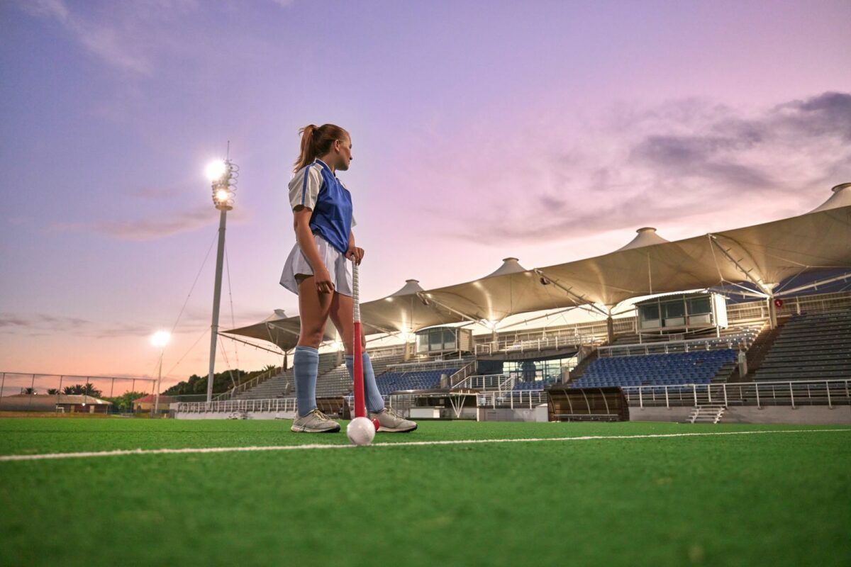 Hockey stadium and woman sports training thinking of game strategy and goal fitness health on green pitch field with sunset sky. Young teenager or athlete girl with training gear for competition. ○ Soccer Blade