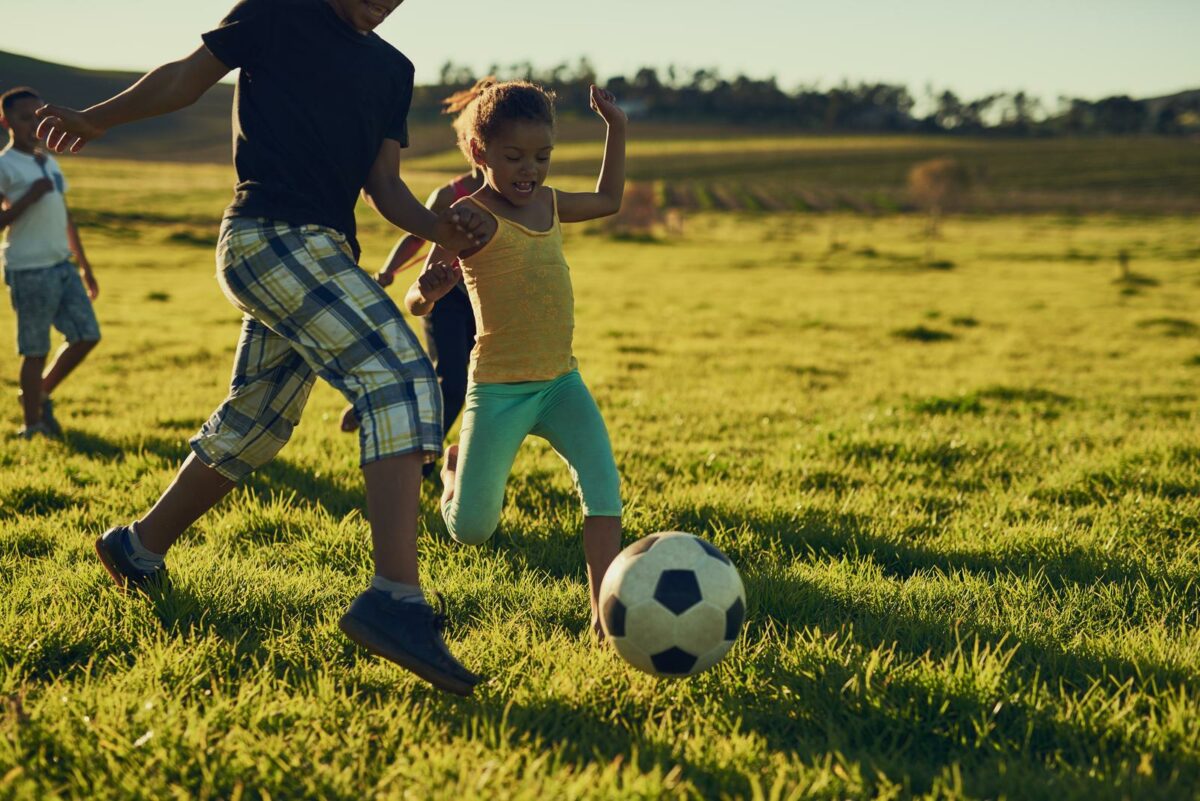 Shot of a group of children playing soccer together in a field outside. ○ Soccer Blade
