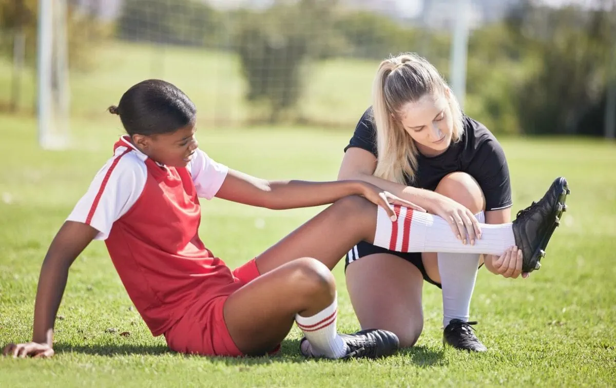 Soccer sports and injury of a female player suffering with sore leg foot or ankle on the field. ○ Soccer Blade