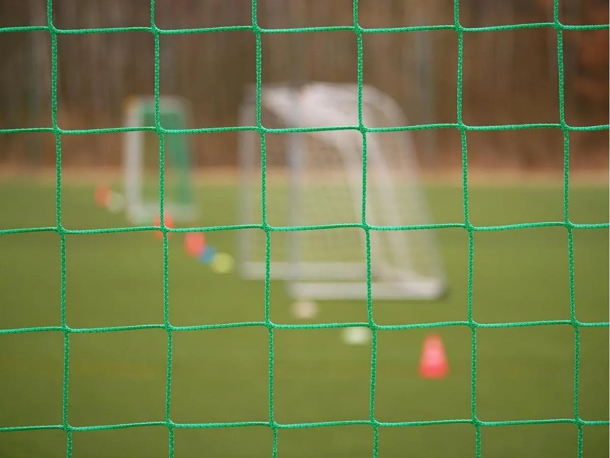 Soccer bounce back nets on a training field with goals in the background. ○ Soccer Blade