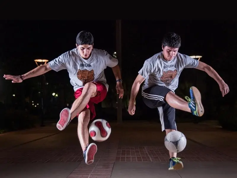 Two soccer players juggling side by side