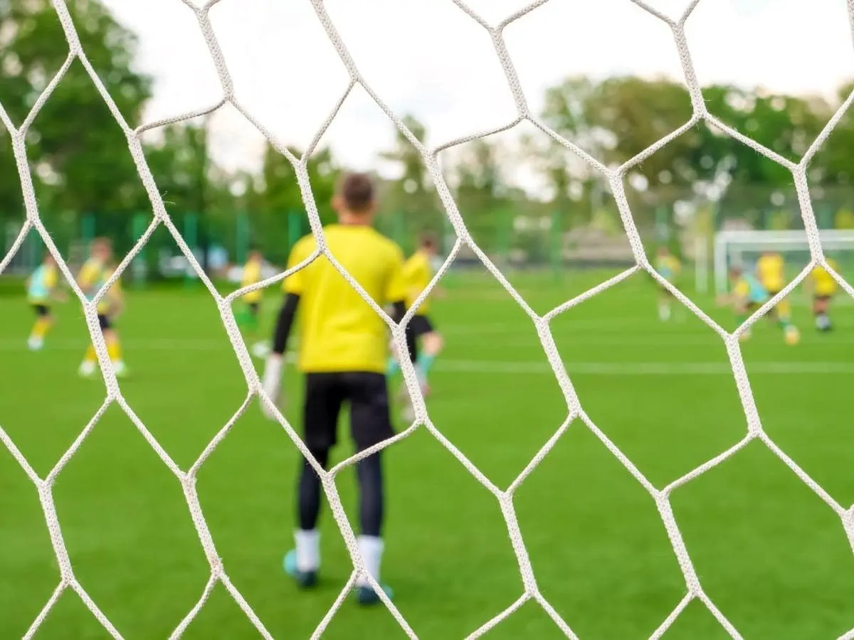 Youth training session from behind a net ○ Soccer Blade