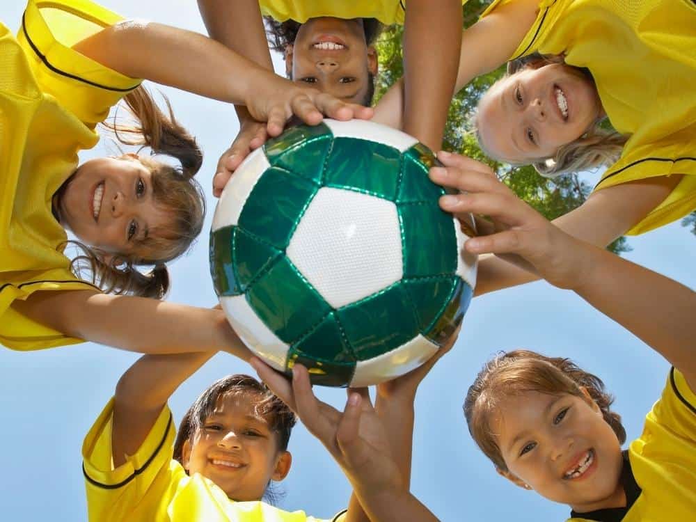 Five Girls Holding a Soccer Ball Looking Down