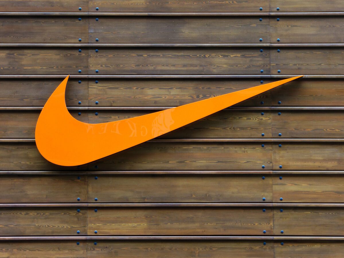 Orange Nike logo on a wooden wall. ○ Soccer Blade