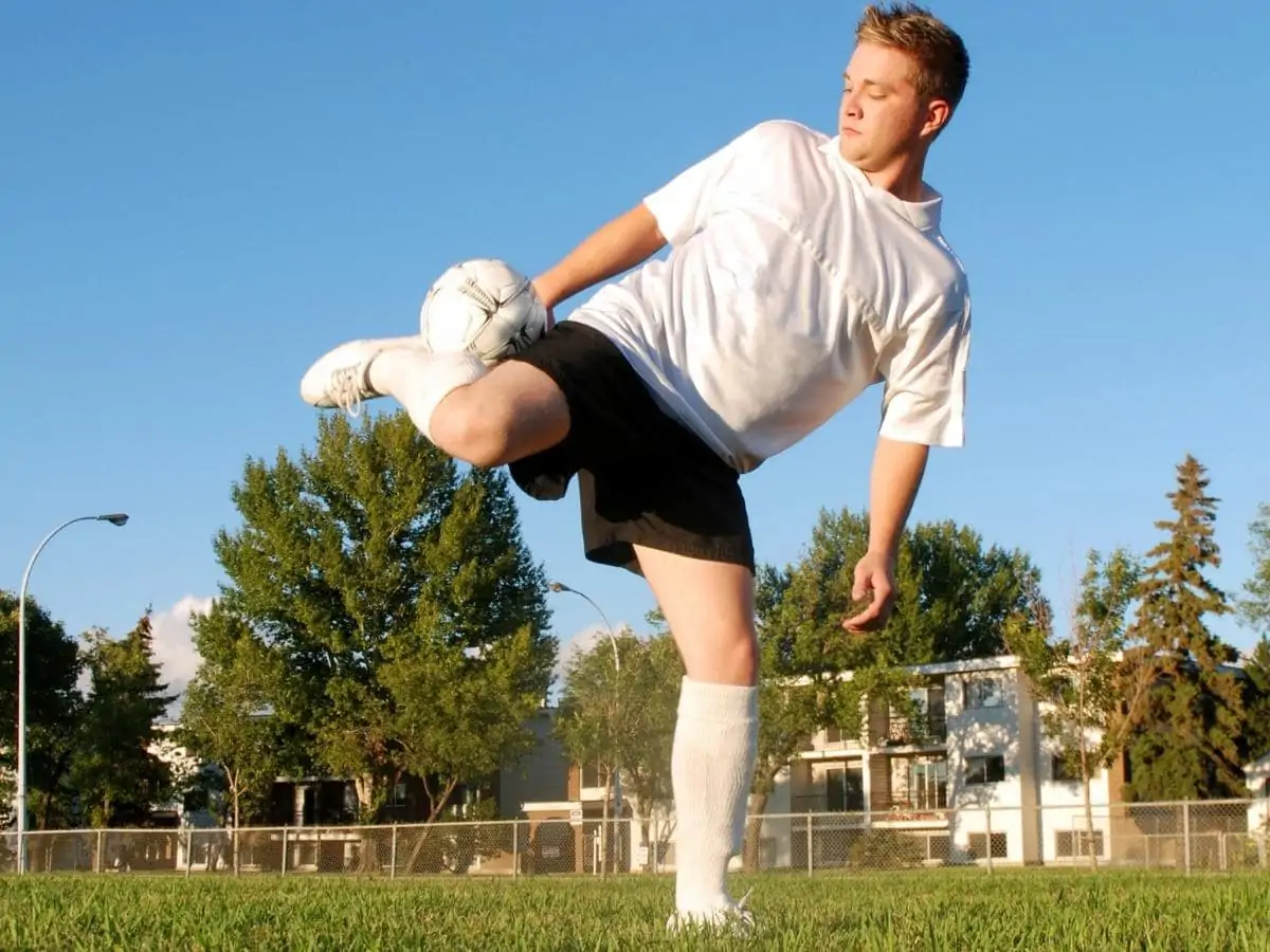 Soccer player juggling a soccer ball with the ball trapped behind his leg. ○ Soccer Blade