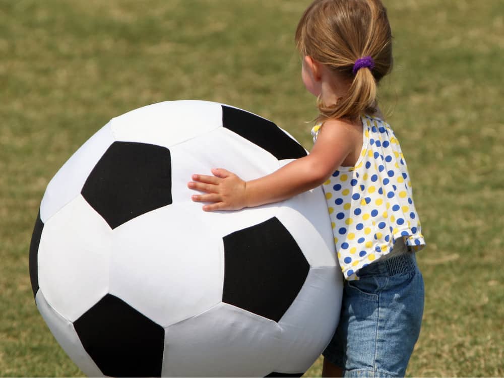 little girl holding giant soccer ball 1