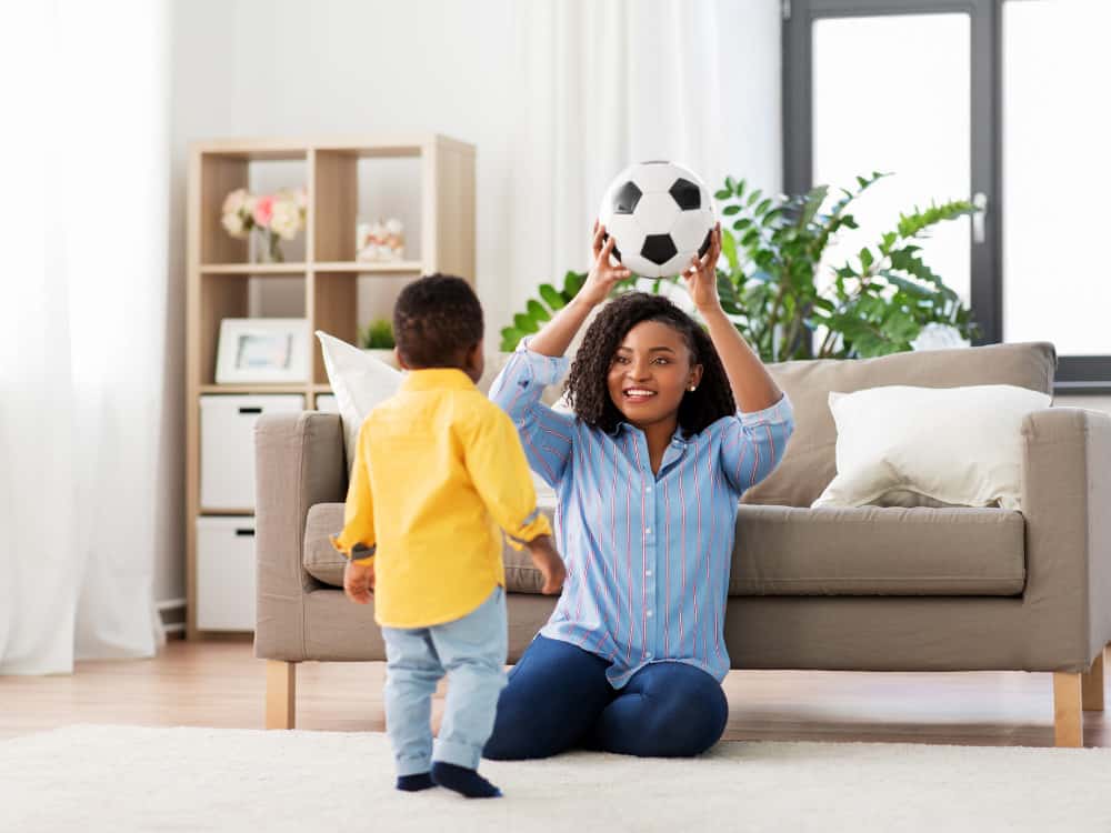 mom playing with soccer ball with toddler son
