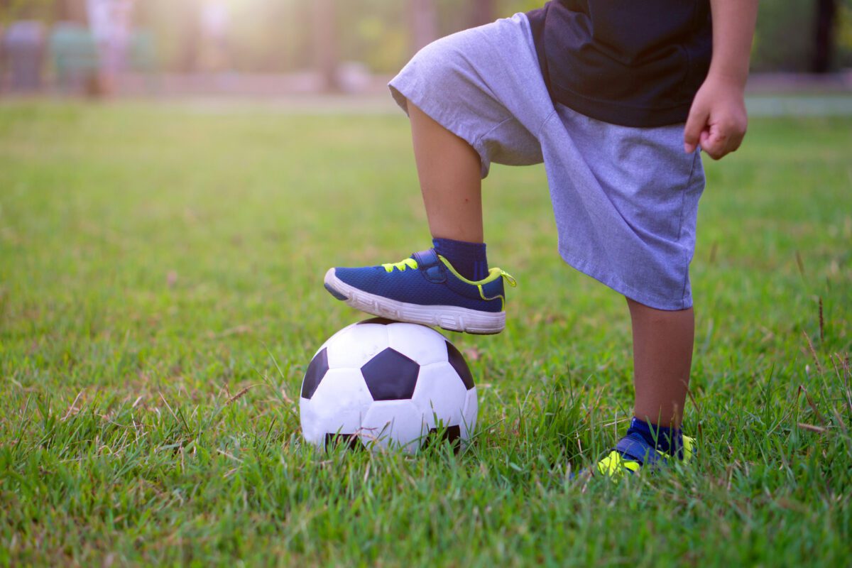 Asian kid playing soccer or football in the park. Step on the ball. ○ Soccer Blade