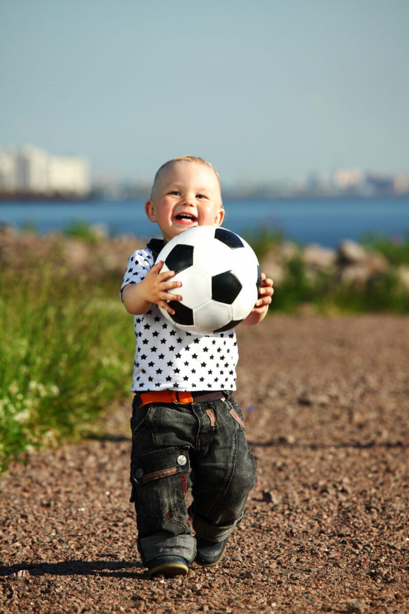 Little boy playing soccer outdoor. ○ Soccer Blade