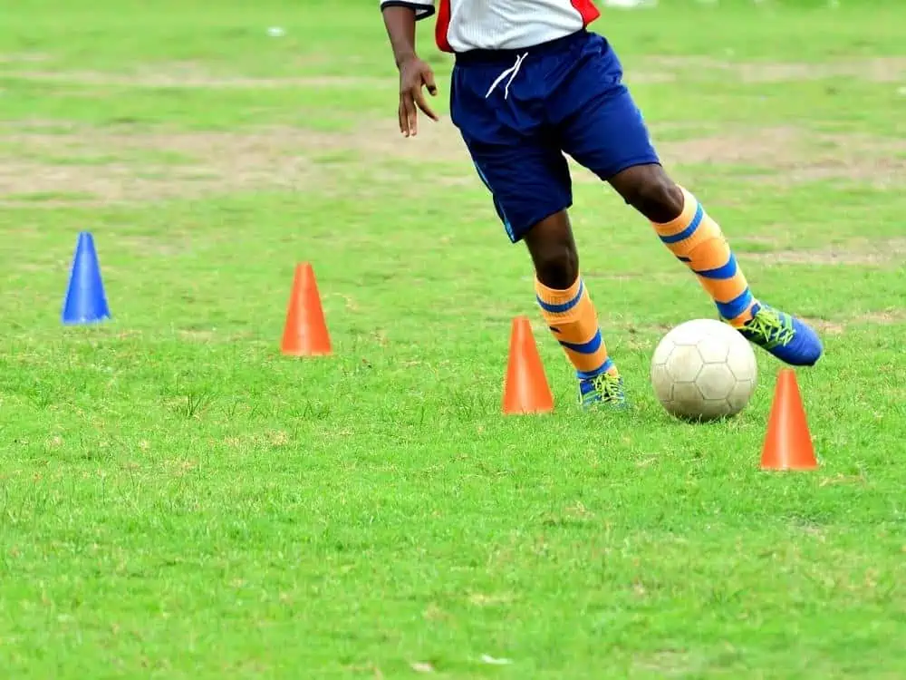 Soccer player dribbling around cones