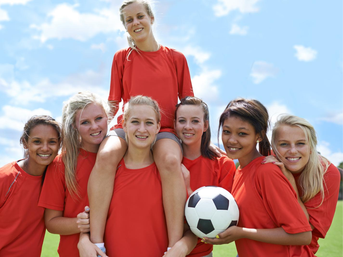 Future pros. Portrait of an all girls soccer team raising their captain after winning a trophy ○ Soccer Blade