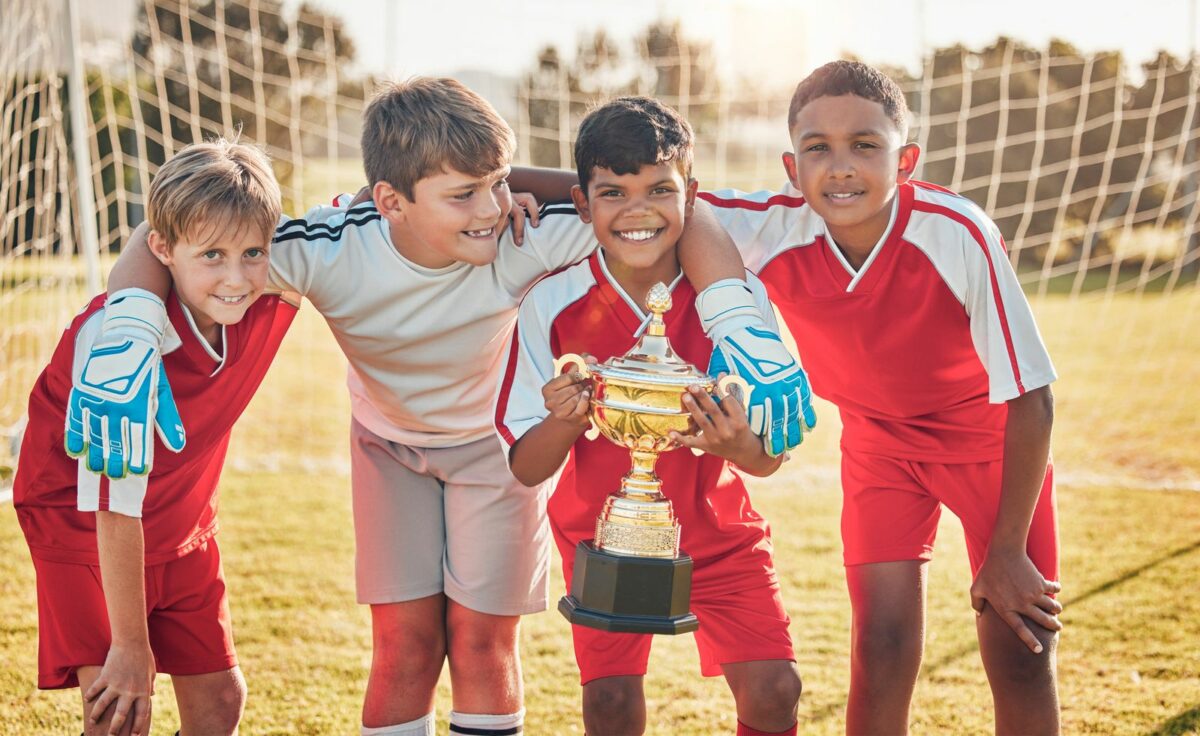 Soccer teamwork and sports with trophy and children at goal post for winner ○ Soccer Blade