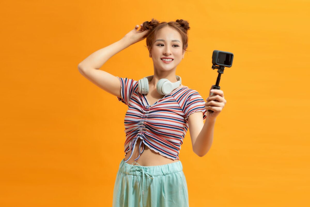 Young woman over yellow background taking pictures on camera ○ Soccer Blade