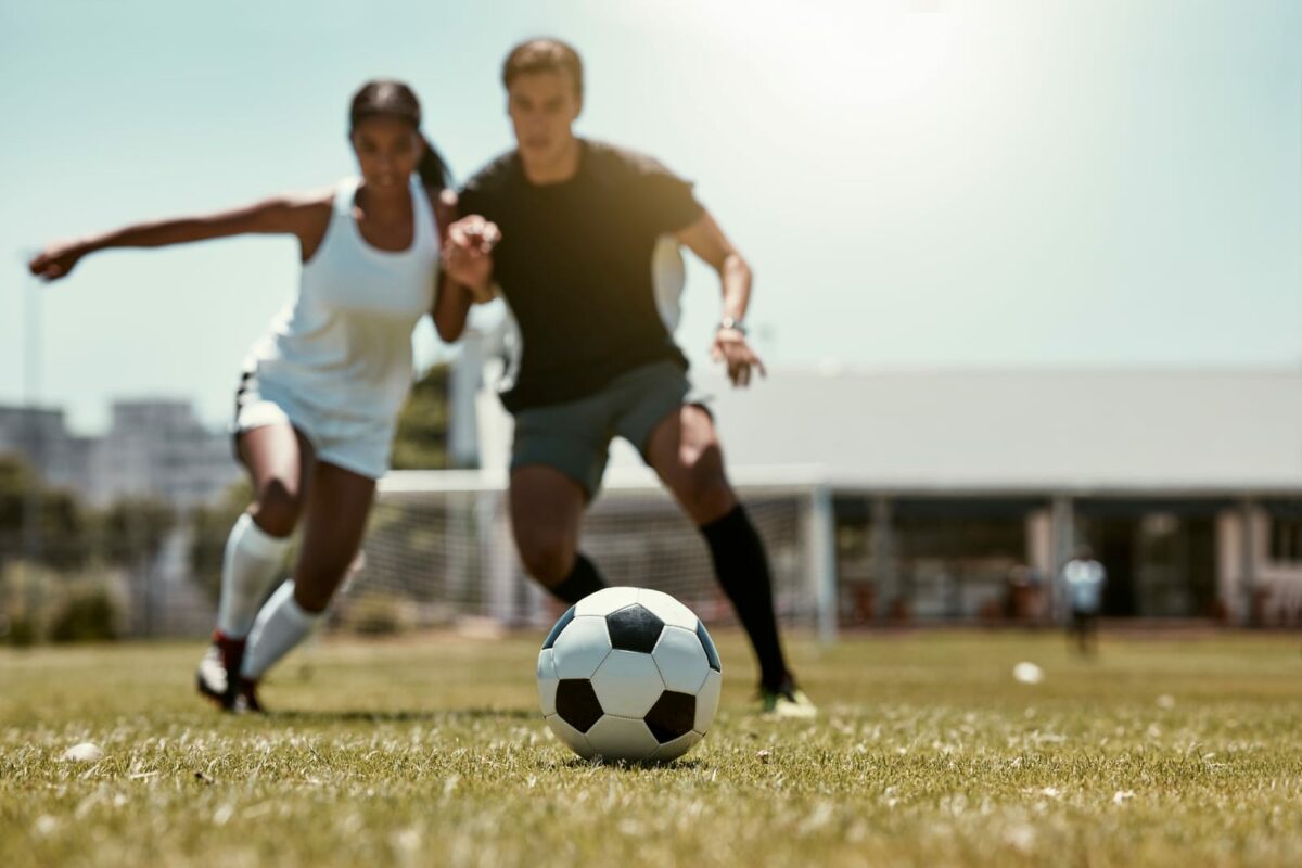 Female and male soccer player shoulder to shoulder on a soccer field ○ Soccer Blade