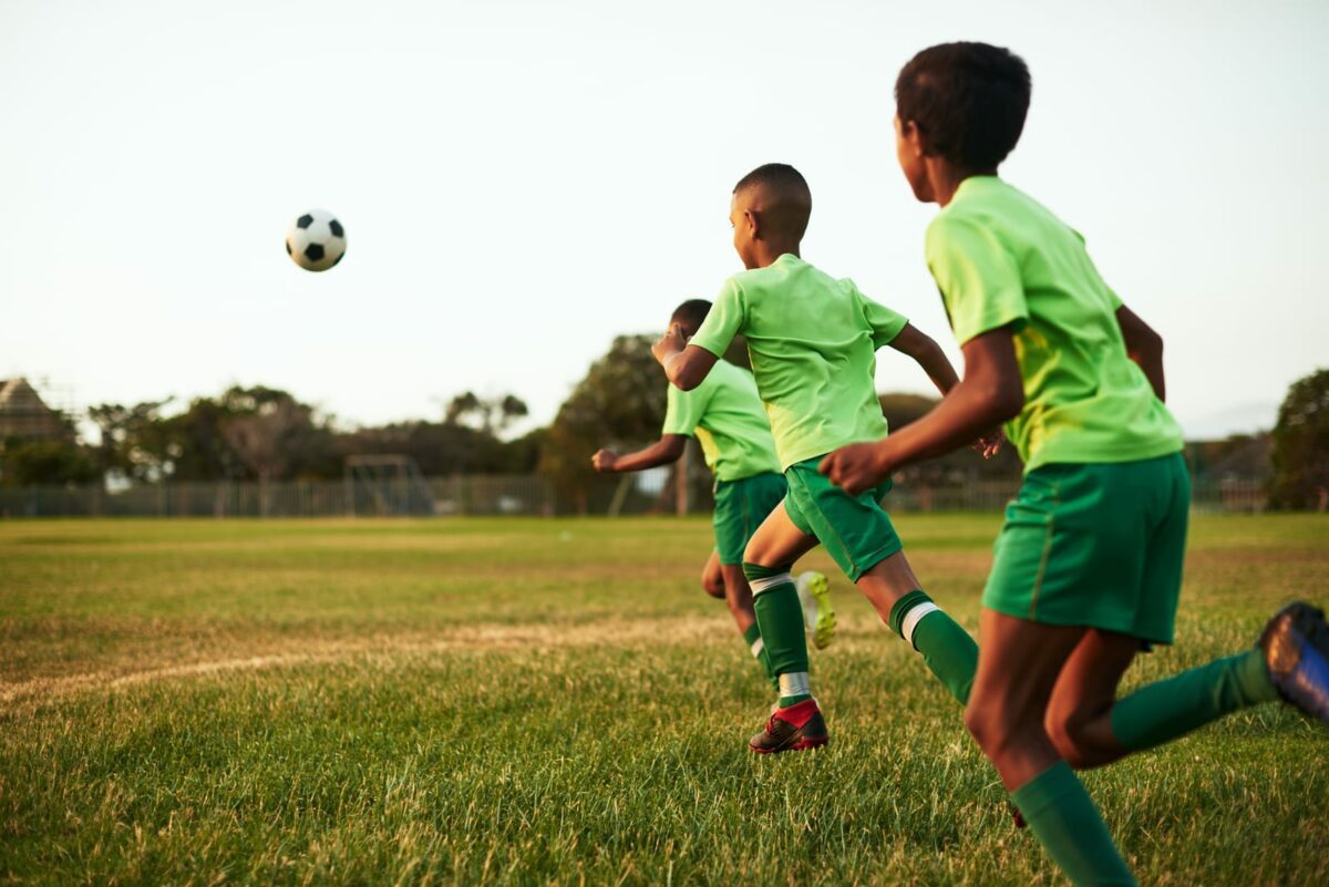 Soccer is excellent exercise for kids. a group of young boys playing soccer on a sports field ○ Soccer Blade