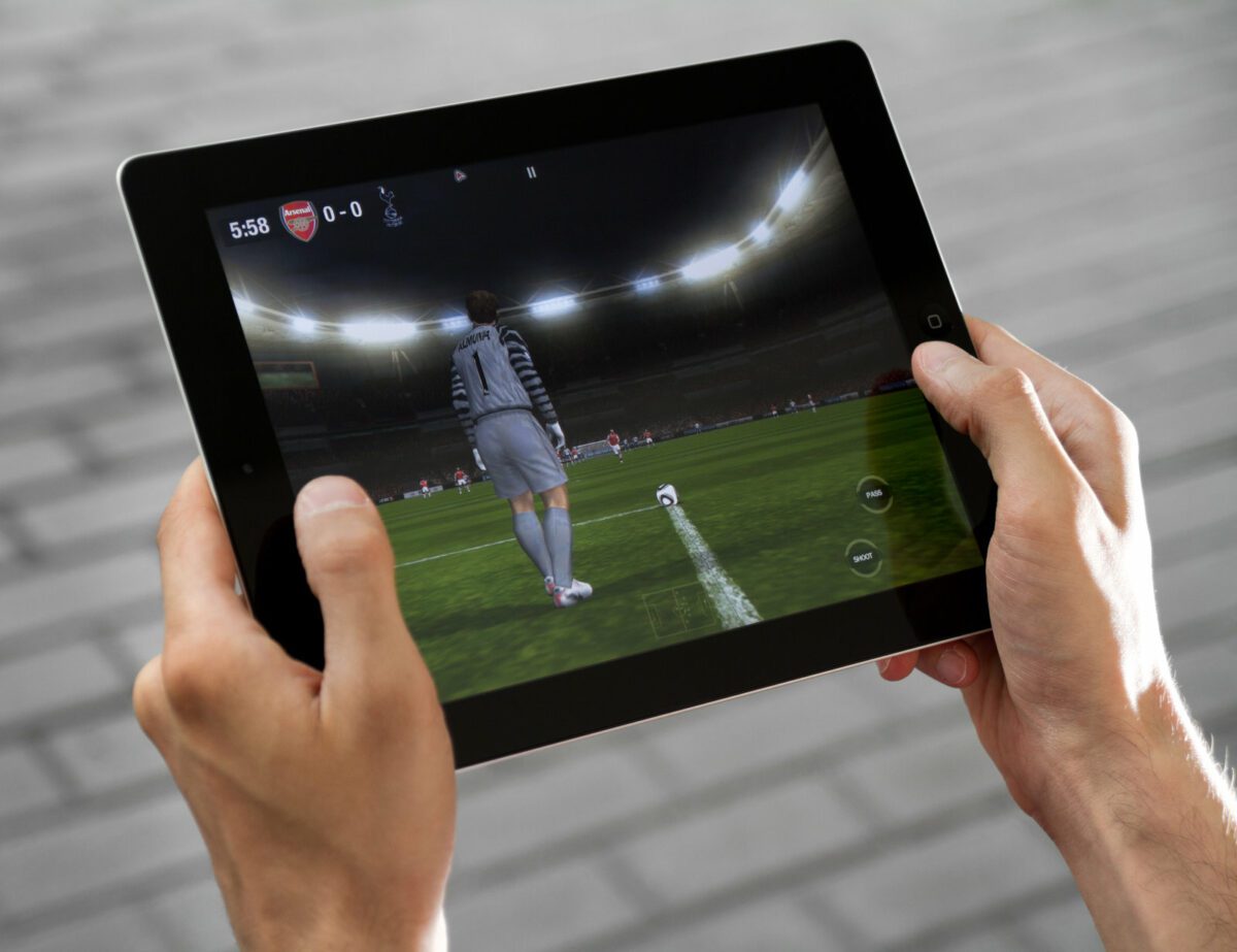 A man outdoors play in the game FIFA football on Apple Ipad2 ○ Soccer Blade